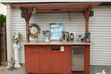 Patio kitchen - mid-sized tropical backyard brick patio kitchen idea in New York with a pergola