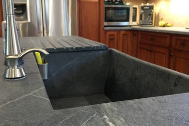 Eat-in kitchen - mid-sized traditional l-shaped marble floor eat-in kitchen idea in Other with a farmhouse sink, medium tone wood cabinets, soapstone countertops, stainless steel appliances and an island