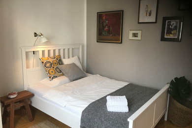 Kleines Skandinavisches Gästezimmer mit grauer Wandfarbe, gebeiztem Holzboden und beigem Boden in Köln