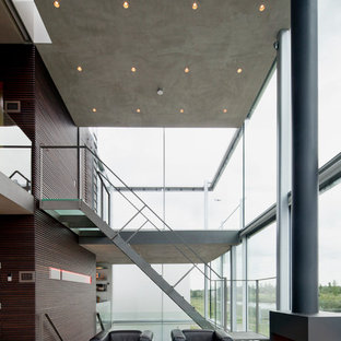 This is an example of a large contemporary formal open plan living room in Frankfurt with brown walls, terracotta flooring, a wood burning stove, a metal fireplace surround, a freestanding tv and beige floors.