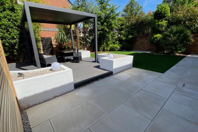 Inspiration for a medium sized contemporary back patio in Essex with natural stone paving and a pergola.
