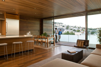 Example of a large minimalist formal and open concept medium tone wood floor living room design in San Francisco with brown walls and no fireplace