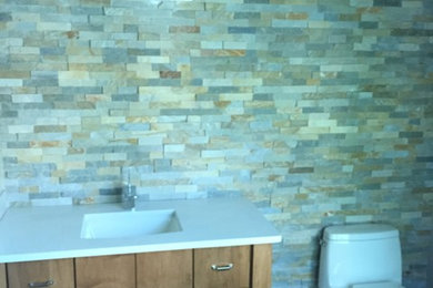 Inspiration for a mid-sized craftsman 3/4 brown tile and stone tile bathroom remodel in New York with an integrated sink, flat-panel cabinets, medium tone wood cabinets and a one-piece toilet