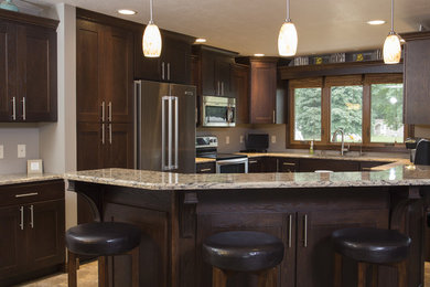 Photo of a large traditional eat-in kitchen in Other with recessed-panel cabinets, dark wood cabinets, stainless steel appliances and with island.