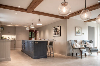 Inspiration for a farmhouse kitchen in Hampshire with shaker cabinets, composite countertops, limestone flooring, an island, beige floors, white worktops, exposed beams and feature lighting.