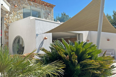 Aménagement d'une grande façade de maison beige méditerranéenne en pierre à un étage avec un toit en tuile et un toit rouge.