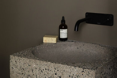 Small minimalist porcelain tile powder room photo in Toronto with recessed-panel cabinets, brown cabinets, a two-piece toilet, gray walls, a wall-mount sink, wood countertops, gray countertops and a floating vanity