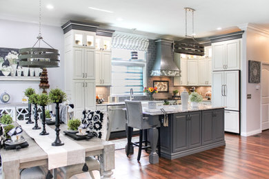 Mid-sized french country l-shaped multicolored floor eat-in kitchen photo in St Louis with a farmhouse sink, raised-panel cabinets, white cabinets, granite countertops, gray backsplash, glass tile backsplash, paneled appliances, an island and white countertops