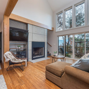 Immagine di un piccolo soggiorno industriale aperto con pareti bianche, pavimento in bambù, camino classico, cornice del camino in cemento, parete attrezzata e pavimento marrone