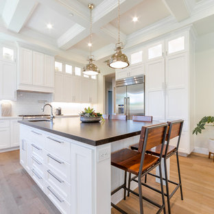 Große Moderne Küche in U-Form mit Vorratsschrank, integriertem Waschbecken, flächenbündigen Schrankfronten, weißen Schränken, Granit-Arbeitsplatte, Küchenrückwand in Weiß, Rückwand aus Keramikfliesen, Küchengeräten aus Edelstahl, hellem Holzboden, Kücheninsel, beigem Boden und weißer Arbeitsplatte in Sacramento