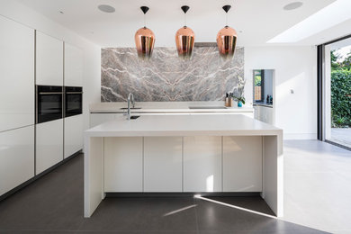 Design ideas for a contemporary l-shaped open plan kitchen in London with an undermount sink, flat-panel cabinets, white cabinets, solid surface benchtops, marble splashback, stainless steel appliances, ceramic floors, with island, grey floor and grey splashback.