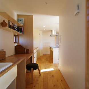 Design ideas for a modern home office and library in Other with a reading nook, white walls, light hardwood flooring, a wood burning stove, a tiled fireplace surround and a built-in desk.