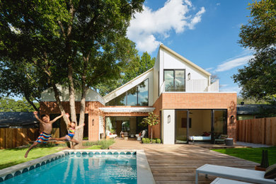 Inspiration for a mid-sized 1960s white two-story brick and clapboard exterior home remodel in Austin with a metal roof and a white roof