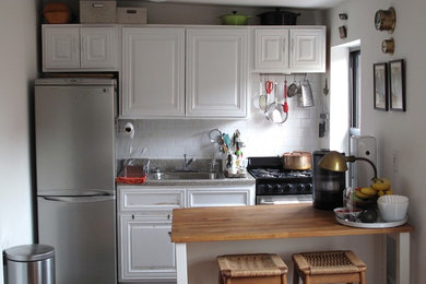 Foto på ett avskilt, litet vintage linjärt kök, med luckor med upphöjd panel och vita skåp