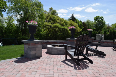 This is an example of a mid-sized traditional backyard patio in Providence with a fire feature, concrete pavers and no cover.