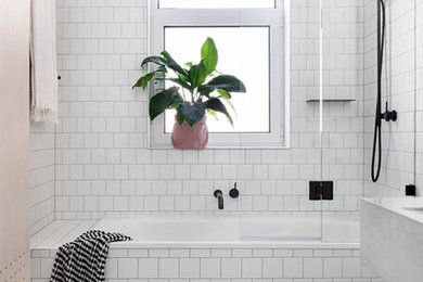 Design ideas for a large transitional master bathroom in Philadelphia with raised-panel cabinets, white cabinets, an alcove tub, a shower/bathtub combo, a one-piece toilet, white tile, ceramic tile, white walls, cement tiles, a wall-mount sink, solid surface benchtops, white floor, a hinged shower door and white benchtops.