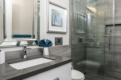 Inspiration for a mid-sized modern master bathroom in Toronto with flat-panel cabinets, white cabinets, an alcove shower, a wall-mount toilet, gray tile, porcelain tile, porcelain floors, an undermount sink, engineered quartz benchtops, grey floor, a sliding shower screen and grey benchtops.