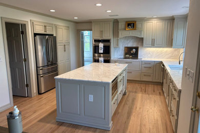 Inspiration for a craftsman medium tone wood floor and brown floor kitchen remodel in Denver with an undermount sink, raised-panel cabinets, green cabinets, quartz countertops, quartz backsplash and stainless steel appliances