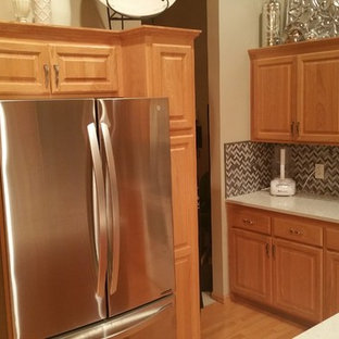 Example of a mid-sized trendy l-shaped light wood floor eat-in kitchen design in Minneapolis with an undermount sink, raised-panel cabinets, light wood cabinets, quartz countertops, gray backsplash, metal backsplash, stainless steel appliances and an island