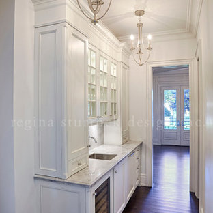 Exemple d'une grande arrière-cuisine chic avec un évier encastré, un placard avec porte à panneau encastré, des portes de placard blanches, un plan de travail en quartz, une crédence en mosaïque, un électroménager encastrable, un sol en bois brun et un îlot central.