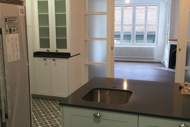Ejemplo de cocina clásica renovada de tamaño medio con fregadero bajoencimera, armarios con paneles con relieve, puertas de armario grises, encimera de granito, salpicadero blanco, salpicadero de azulejos de cerámica, electrodomésticos de acero inoxidable, suelo de azulejos de cemento, península y suelo multicolor