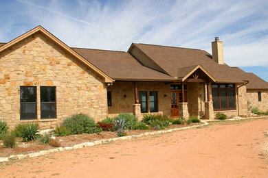 This is an example of a large transitional one-storey beige house exterior in Austin with stone veneer and a shingle roof.