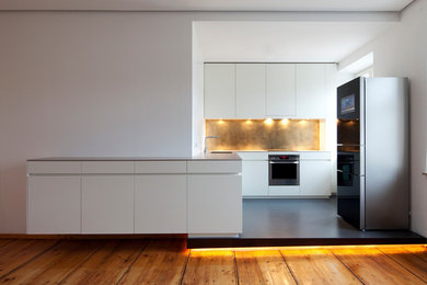 Offene Moderne Küche in L-Form mit Unterbauwaschbecken, flächenbündigen Schrankfronten, weißen Schränken, Mineralwerkstoff-Arbeitsplatte, Küchenrückwand in Metallic, Küchengeräten aus Edelstahl und Linoleum in München