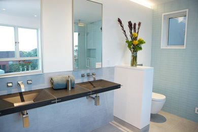 Inspiration for a large modern master bathroom in San Francisco with glass-front cabinets, a freestanding tub, a curbless shower, a wall-mount toilet, green tile, glass tile, white walls, ceramic floors, a wall-mount sink, granite benchtops, grey floor and a hinged shower door.