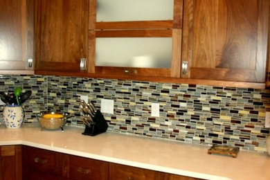Enclosed kitchen - mid-sized traditional u-shaped beige floor enclosed kitchen idea in Albuquerque with dark wood cabinets, stainless steel appliances, an island, an undermount sink, shaker cabinets, solid surface countertops, multicolored backsplash and glass tile backsplash