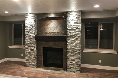 Large classic open plan games room in Salt Lake City with green walls, ceramic flooring, a standard fireplace, a tiled fireplace surround, no tv and brown floors.