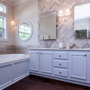 Immagine di una stanza da bagno padronale moderna di medie dimensioni con ante bianche, top in superficie solida, piastrelle grigie, piastrelle in pietra, pareti beige e parquet scuro