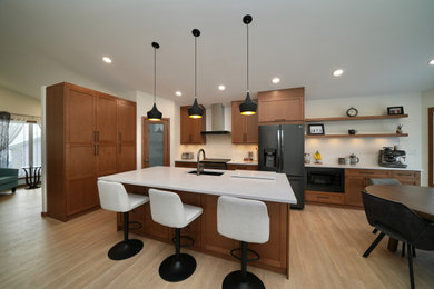 Inspiration for a l-shaped vinyl floor and beige floor eat-in kitchen remodel in Other with a single-bowl sink, shaker cabinets, brown cabinets, quartz countertops, white backsplash, ceramic backsplash, black appliances, an island and white countertops