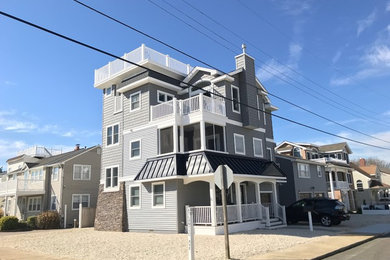Mid-sized coastal gray three-story vinyl exterior home idea in New York with a shingle roof