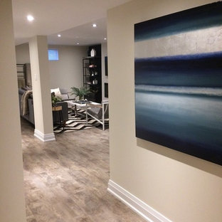 Large classic look-out basement in Toronto with grey walls, laminate floors, a hanging fireplace, a plastered fireplace surround and grey floors.