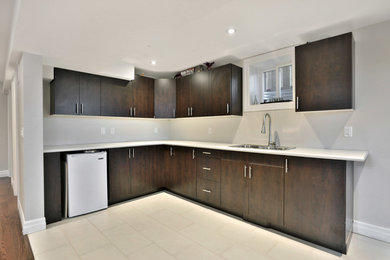 This is an example of a mid-sized modern l-shaped eat-in kitchen with a double-bowl sink, brown cabinets, quartz benchtops and multi-coloured floor.
