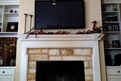 Example of a mid-sized mountain style enclosed dark wood floor family room design in Austin with beige walls, a standard fireplace, a wood fireplace surround and a wall-mounted tv