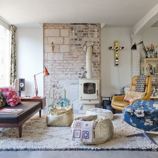 Imagen de salón para visitas cerrado, ecléctico, grande, sin televisor, con paredes blancas, suelo de cemento y estufa de leña