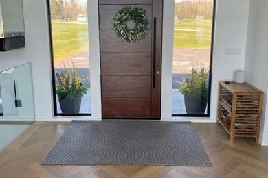 Foto de distribuidor contemporáneo grande con paredes blancas, suelo de madera clara, puerta simple, puerta de madera en tonos medios y suelo beige