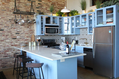 Eat-in kitchen - mid-sized transitional u-shaped concrete floor and beige floor eat-in kitchen idea in Atlanta with an undermount sink, glass-front cabinets, blue cabinets, quartzite countertops, multicolored backsplash, ceramic backsplash, stainless steel appliances, a peninsula and white countertops