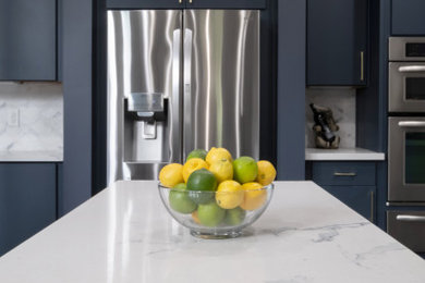 Trendy kitchen photo in Wilmington with flat-panel cabinets, blue cabinets, white backsplash and white countertops