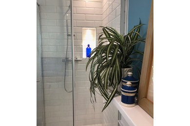 ロンドンにあるお手頃価格の中くらいなトラディショナルスタイルのおしゃれなバスルーム (浴槽なし) (フラットパネル扉のキャビネット、白いキャビネット、珪岩の洗面台、コーナー設置型シャワー、白いタイル、セラミックタイル、開き戸のシャワー、白い洗面カウンター、一体型トイレ	、青い壁、クッションフロア、ベージュの床) の写真