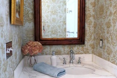 This is an example of a small traditional powder room in New York with recessed-panel cabinets, white cabinets, an undermount sink, marble benchtops and multi-coloured walls.