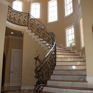 Medium sized mediterranean wood curved metal railing staircase in Orlando with marble risers.
