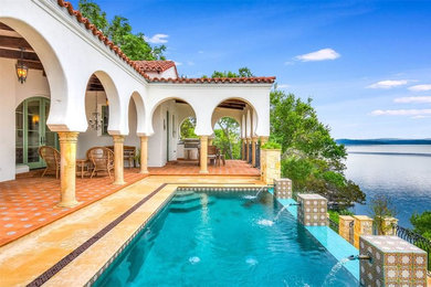 Example of a large tuscan backyard tile and rectangular infinity pool fountain design in Austin