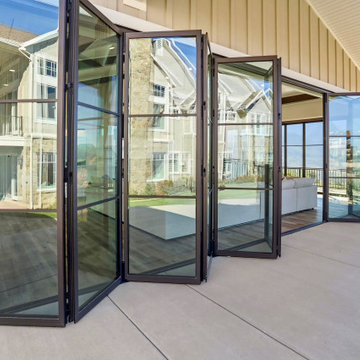 Bronze Folding Glass Panels Stack Outward Against the Pavilion Wall by the Pool