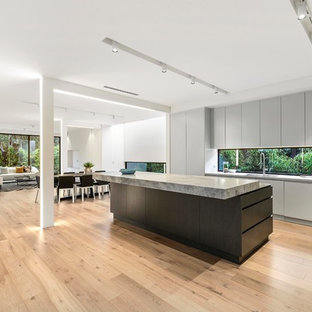 Exempel på ett mellanstort modernt grå linjärt grått skafferi, med en undermonterad diskho, grå skåp, bänkskiva i kalksten, grått stänkskydd, glaspanel som stänkskydd, rostfria vitvaror, mellanmörkt trägolv och en köksö
