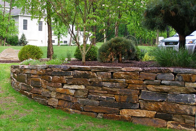 Imagen de jardín tradicional en patio lateral con muro de contención y adoquines de piedra natural