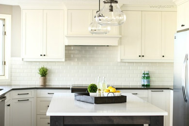 Inspiration for a large transitional u-shaped medium tone wood floor eat-in kitchen remodel in Calgary with an undermount sink, shaker cabinets, white cabinets, quartzite countertops, white backsplash, ceramic backsplash, stainless steel appliances and an island