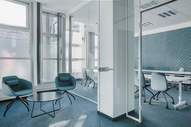 Großes Modernes Arbeitszimmer mit Arbeitsplatz, blauer Wandfarbe, Teppichboden, freistehendem Schreibtisch, Kassettendecke und Wandpaneelen in Berlin