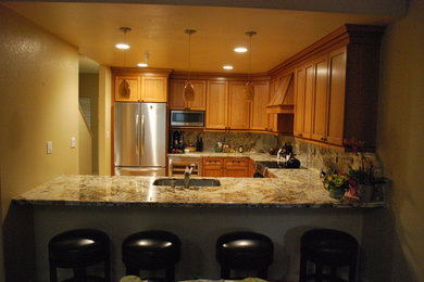 Example of a mid-sized trendy l-shaped eat-in kitchen design in San Francisco with a drop-in sink, recessed-panel cabinets, medium tone wood cabinets, granite countertops, multicolored backsplash, marble backsplash, stainless steel appliances and no island